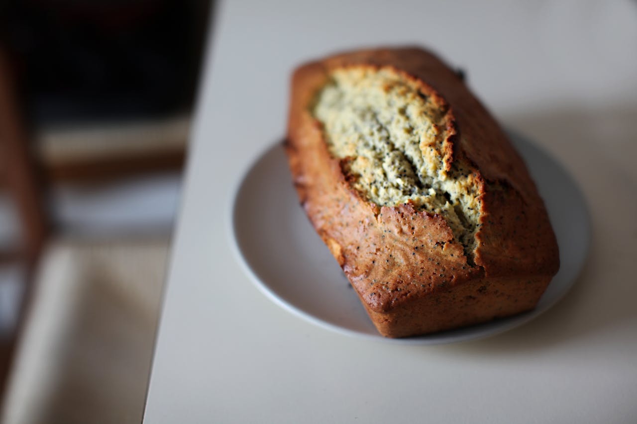 Freshly baked banana bread with a golden-brown crust on a white plate.